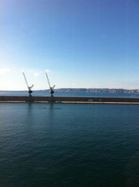 Traditional windmill by lake against clear blue sky