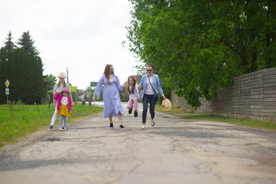 Group of happy family people-two sisters and little girls walking down the city street 