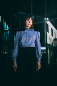 Woman looking away while standing against wall