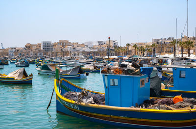 Boats moored in harbor against clear blue sky