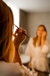 Woman applying make-up while looking in mirror