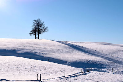 Snow covered field against clear blue sky