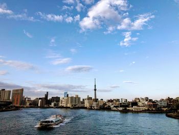 Boats in river by buildings in city against sky