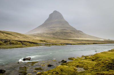 Scenic view of lake by mountain against sky