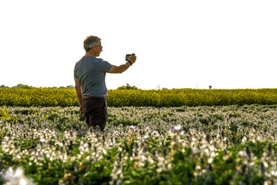 Man photographing on field against clear sky