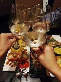 Close-up of hand holding wine glasses on table