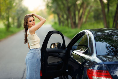 Side view of young woman sitting on car
