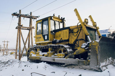 Abandoned train on snow covered land against sky