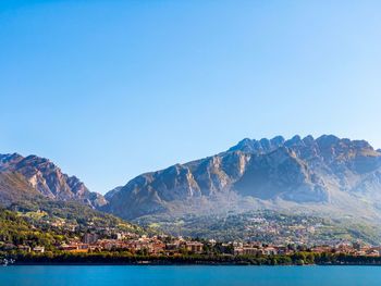 Scenic view of sea and mountains against clear blue sky