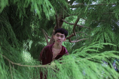 Stylish man and expressing himself in green leaf branches looks cool