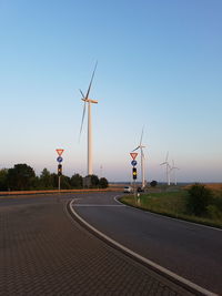 Windmill on road against clear sky