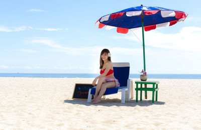 Woman sitting on chair at beach