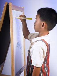 Boy drawing on canvas against wall