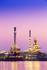 Illuminated factory against sky at night