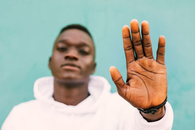 Close-up portrait of man gesturing against wall