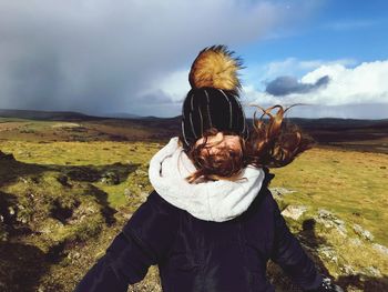 Portrait of girl in warm clothing on field against sky