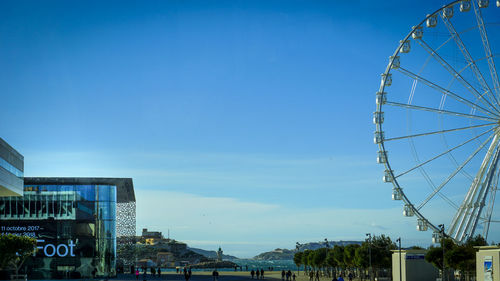 Low angle view of ferris wheel against blue sky