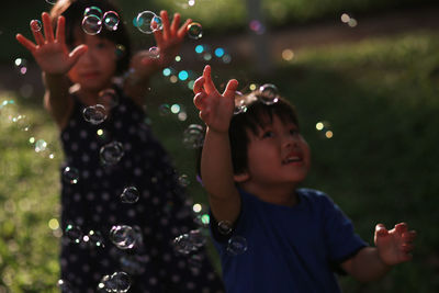 High angle view of siblings playing with bubbles at park