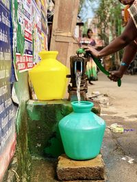 Midsection of woman filling water on footpath