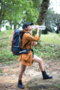 Woman drinking water while hiking in forest
