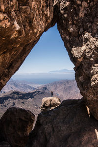 Mid distance view of woman standing on rock formation