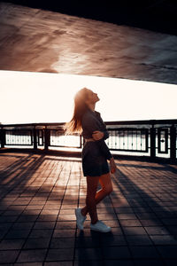 Full length of woman standing on footpath against sky