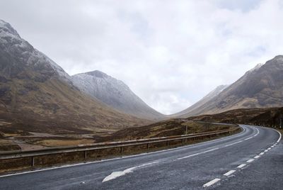 Road by mountains against sky