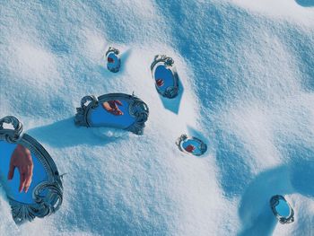 High angle view of mirrors with hand reflection on snow