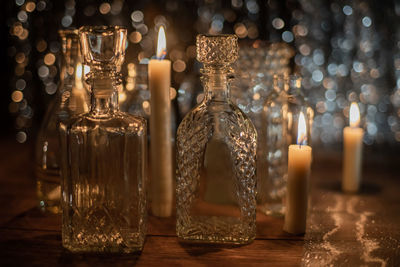 Close-up of candles burning by glass bottles on table