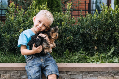 Boy with yorkshire terrier dog puppy. cute baby boy hugs york terrier puppy 