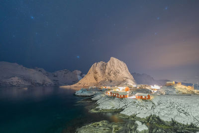 Scenic view of sea and mountains against sky at night