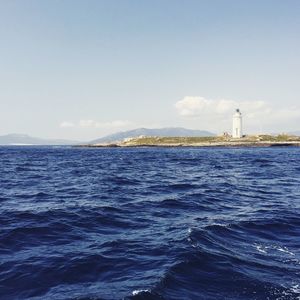 Surface level of calm blue sea with lighthouse in distance