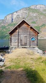 House on shore by mountain against sky