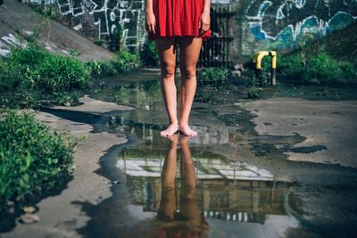 Low section of woman standing in puddle