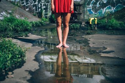 Low section of woman standing in puddle