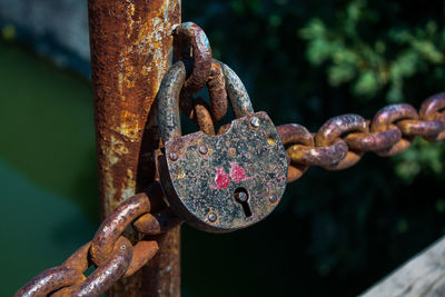 Close-up of rusty chain hanging on railing