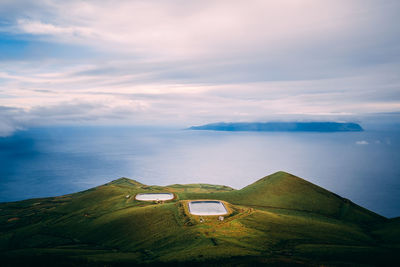 Scenic view of mountain and sea against cloudy sky