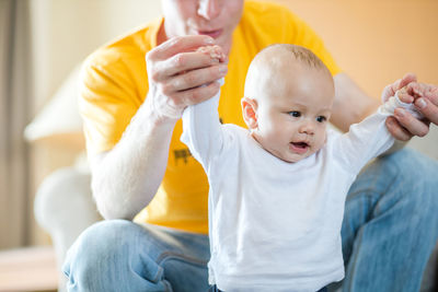 Midsection of father holding son hands