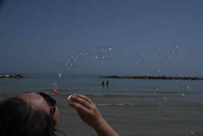 Rear view of woman blowing bubbles at beach