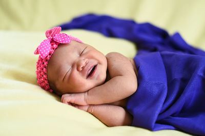 Close-up of baby girl sleeping on bed at home