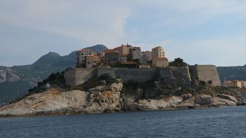 Buildings by sea against sky