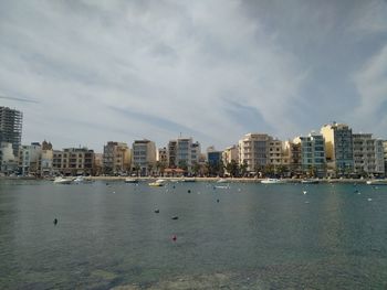 Sea by cityscape against sky