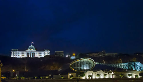 Illuminated building against blue sky at night
