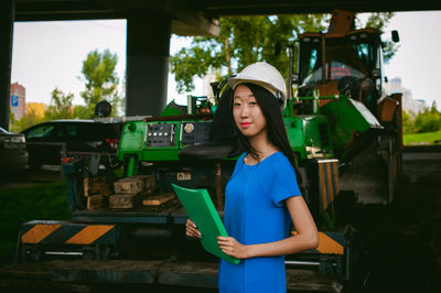 Female architect standing against vehicle