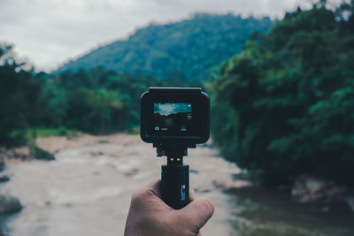 Person photographing camera against trees