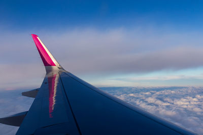 Cropped image of aircraft wing flying against sky