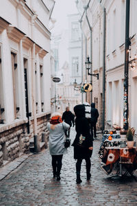 Rear view of people walking on street amidst buildings