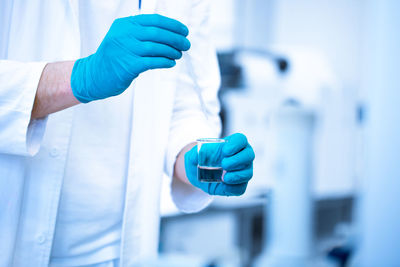 Midsection of scientist holding vial in laboratory