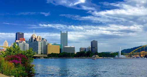 City at waterfront against cloudy sky