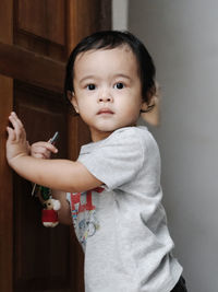 Portrait of cute girl with arms crossed against wall